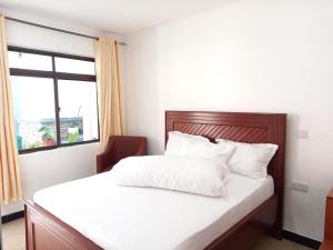 sypialnia z łóżkiem z białą pościelą i oknem w obiekcie Didas Villa w mieście Arusza