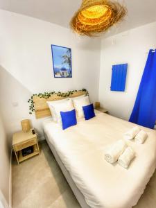 a bedroom with a large white bed with blue pillows at Le Santorini - centre ville & terrasse privée in Béthune