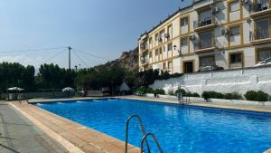 a large blue swimming pool next to a building at Troglorent - Maison Troglodyte in Terque