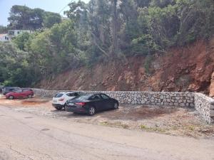 two cars parked next to a stone wall on a road at Agape Rose Hotel in Tivat