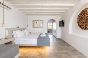 ein weißes Schlafzimmer mit einem Bett und einem Tisch in der Unterkunft Villa Ava Mykonos in Mykonos Stadt