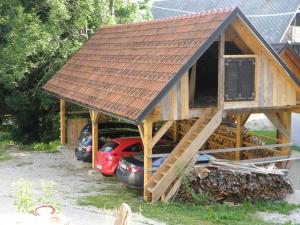 a house with a roof on top of some cars at Tubej turist farm - wooden hayloft in Bohinjska Bistrica