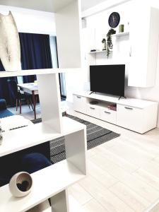 a living room with white furniture and a tv at Global Residence in Bucharest