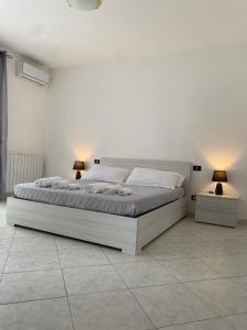 a white bedroom with a large bed with two lamps at [la terrazza del sole] in Menfi