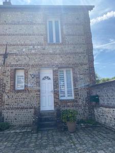 une maison en briques avec une porte blanche et une plante en pot dans l'établissement Neuville secrete, à Dieppe