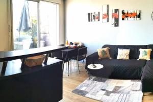 uma sala de estar com um sofá preto e uma mesa em Superbe 3 pièces (2 chambres et salon) + Terrasse 50 m² 6 minutes du centre ville em Bordeaux