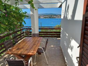 a wooden table and chairs on a porch with a view of the water at Apartment Bella in Trogir