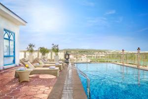 a pool with couches and chairs next to a building at Vivanta Jammu City Centre in Jammu