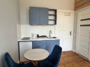 a small kitchen with a table and blue chairs at Agapella Apartamenty- Foksal Sopot Rooms in Sopot