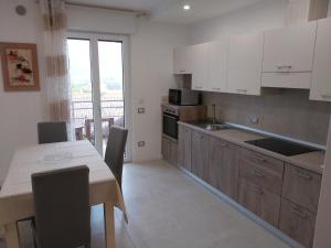 a kitchen with white cabinets and a table with chairs at Ca Giardina in Levico Terme