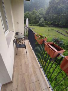 Un balcón con una mesa y una silla sobre una valla en Mieszkanie 50M, en Rymanów-Zdrój