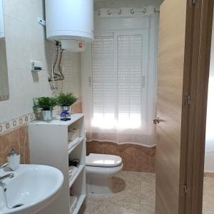 La salle de bains est pourvue de toilettes blanches et d'un lavabo. dans l'établissement Apt. cerca de la playa y airport, à Malaga