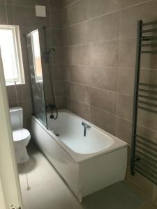 ein Bad mit einer Badewanne und einem WC in der Unterkunft Three Kings Luxe Escape in London