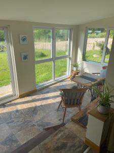 a living room with windows and a table and chairs at Moorland Breeze in Bodmin