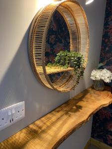un espejo de mimbre colgado en una pared con una mesa de madera en Moorland Breeze en Bodmin