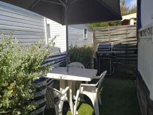 a table and chairs under an umbrella in a backyard at Le Paradis Bleu camping les pins maritimes in Hyères +7 photos