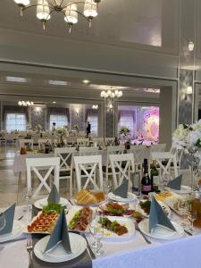 ein Esszimmer mit einem Tisch und Teller mit Lebensmitteln in der Unterkunft Готель Максим Ресторан in Drogovyzhe