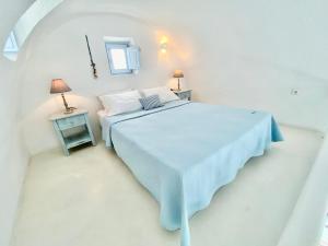 a white bedroom with a bed and a mirror at Heliades Apartments in Imerovigli