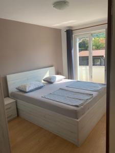 ein großes Bett in einem Schlafzimmer mit Fenster in der Unterkunft Apartments Nautica in Barbat na Rabu