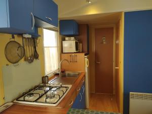 a kitchen with a stove and a sink and blue cabinets at Le Paradis Bleu camping les pins maritimes in Hyères