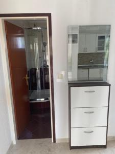 ein Badezimmer mit einer Kommode und einer Glastür in der Unterkunft Apartments Nautica in Barbat na Rabu