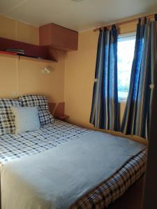 a bedroom with a bed with blue curtains and a window at Le Paradis Bleu camping les pins maritimes in Hyères