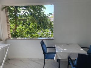 einen Tisch und Stühle in einem Zimmer mit Fenster in der Unterkunft Apartments Nautica in Barbat na Rabu