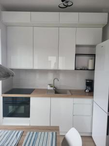 une cuisine avec des armoires blanches et un évier dans l'établissement Bursztynek - Luxoro Park, à Ustka 9 autres photos