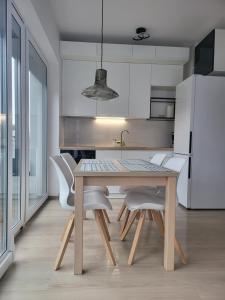 une cuisine avec une table, des chaises et un réfrigérateur dans l'établissement Bursztynek - Luxoro Park, à Ustka