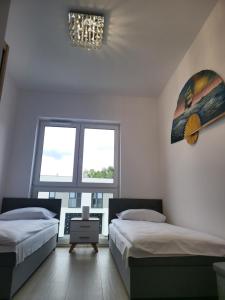 une chambre avec deux lits et un lustre dans l'établissement Bursztynek - Luxoro Park, à Ustka
