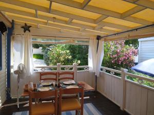 a porch with a table and chairs on it at Le Paradis Bleu camping les pins maritimes in Hyères