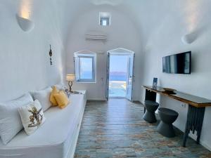 ein Wohnzimmer mit einem weißen Sofa und einem TV in der Unterkunft Heliades Apartments in Imerovigli