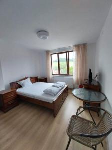 een slaapkamer met een bed, een tafel en een stoel bij Kъща за гости Демария in Koprivshtitsa