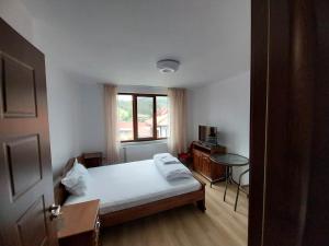 Schlafzimmer mit einem Bett, einem Tisch und einem Fenster in der Unterkunft Kъща за гости Демария in Kopriwschtiza