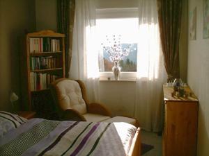 a bedroom with a bed and a window and a chair at Schnuckliges Apartment mit Traum-Panorama im Harz in Sankt Andreasberg