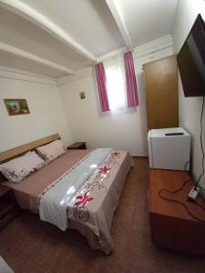 a bedroom with a bed and a flat screen tv at D&M in Neptun