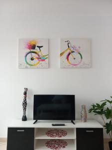 a living room with a tv and two paintings on the wall at Playa Caosa in San Ciprián