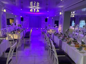 ein Esszimmer mit weißen Tischen und violetter Beleuchtung in der Unterkunft Готель Максим Ресторан in Drogovyzhe