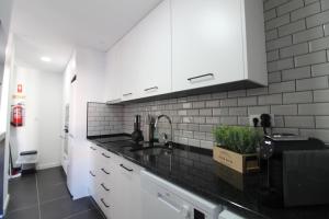 a kitchen with a sink and white cabinets at Varanda do Bonfim in Setúbal
