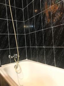 baño con pared de azulejos negros y bañera en Apartament al cor de la Vall de Camprodon, en Vilallonga de Ter