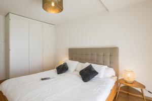 1 dormitorio con 1 cama blanca y 2 almohadas en Blonay Garden Apartment - Swiss Hotel Apartments en Blonay