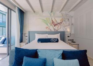 een slaapkamer met een groot bed met blauwe kussens bij Hotel Tide Phuket Beach Front in Phuket