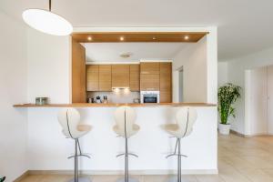 a kitchen with three stools in front of a counter at Blonay Garden Apartment - Swiss Hotel Apartments in Blonay