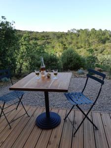 drewniany stół z 2 krzesłami i butelką wina w obiekcie Gîte Côté Nature w mieście Cabrerolles