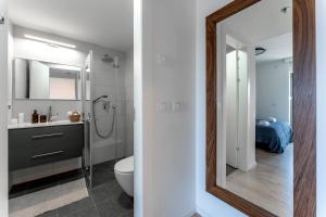 a bathroom with a sink and a toilet and a mirror at Holysuite Savyon View Tower in Jerusalem +96 photos