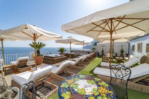 a patio with chairs and umbrellas and the ocean at Villa Nina in Positano