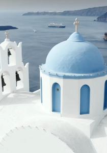 una capilla blanca con una cúpula azul en la isla de Santorini en Nelya Suites, en Megalokori