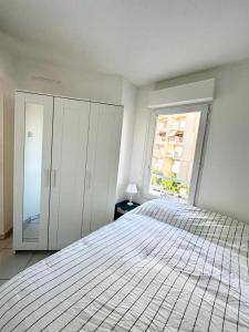 ein weißes Schlafzimmer mit einem Bett und einem Fenster in der Unterkunft Studio Cabine Plein centre JUAN LES PINS in Antibes