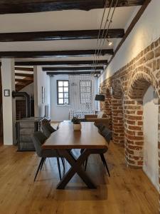 a dining room with a wooden table and a brick wall at BacksteinFlair - LüneMitte in Lüneburg