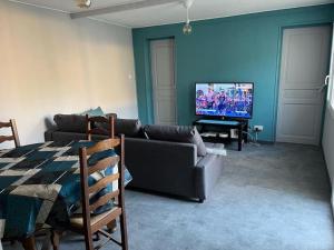 a living room with a couch and a television at Langeais - Gîte des Culeveaux in Langeais